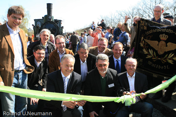 Der offizielle Eröffnungsakt: In der ersten Reihe v.l.: Oliver Wolff (Ministerium für Bauen und Verkehr des Landes NRW), Peter Koester (Bürgermeister der Stadt Waldbröl), Gerhard Mansel (Vorsitzender des Förderkreises zur Rettung der Wiehltalbahn e.V.) und Bernd Kronenberg (Ehrenvorsitzender des Förderkreises). In der zweiten Reihe u.a. Friedrich Wilke (stv. Landrat des Oberbergischen Kreises) und Rüdiger Gennies (Bürgermeister der Gemeinde Reichshof). Rechts hält Thomas Philipp, Schriftführer der IG Bw Dieringhausen, die fast 100 Jahre alte Fahne des Eisenbahnervereins Waldbröl. Das Eisenbahnmuseum hat die Fahne an den Wiehltalbahn-Förderkreis zur Ausstellung in Waldbröl übergeben.