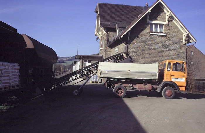 Beim Landwarenhandel setzt beim Anblick des Zuges hektische Betriebsamkeit ein: Güterwagen müssen noch schnell entladen werden. Könnten sie nicht von diesem Güterzug mitgenommen werden, würden Standgelder anfallen.